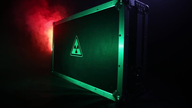 Radioactive (atomic ionizing radiation) danger warning symbol in triangular on a black case. Black suitcase with a sign of radiation hazard. Dark background.