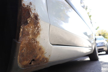 Grey car with rust on door sill and fender