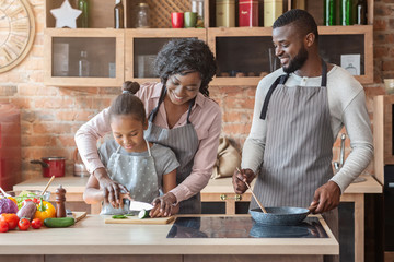 Mother showing daughter how to cut cucumber