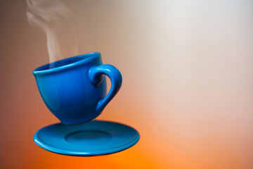 Floating blue cup of espresso. Mock up of soaring in the air cup of hot coffee