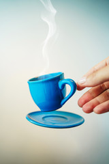 Floating blue cup of espresso with hands. First-person view. Mock up of soaring in the air cup of hot coffee. Levitate concept