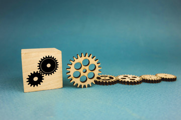 five wooden gears and one gear on a cube on a blue background.
