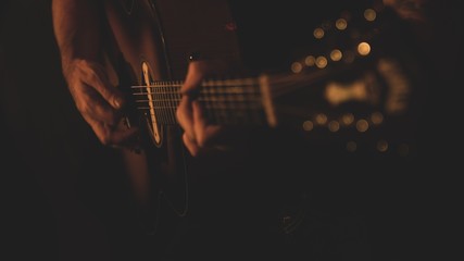 Selective shot of a musician playing on an acoustic guitar with his hands visible
