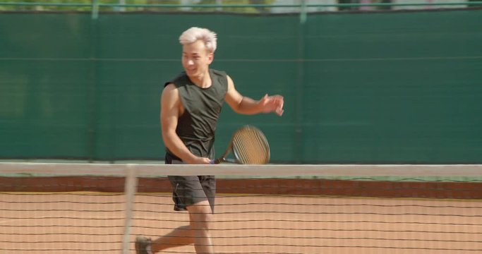 A Tennis player volleys at the net and celebrates in slow motion.