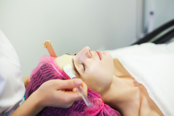 Spa therapy for young woman having facial mask at beauty salon.