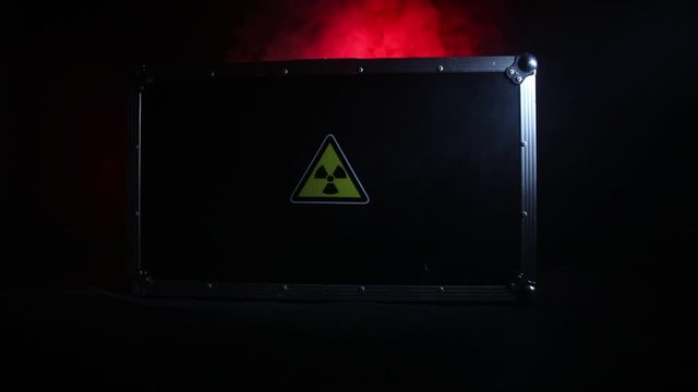 Radioactive (atomic ionizing radiation) danger warning symbol in triangular on a black case. Black suitcase with a sign of radiation hazard. Dark background.