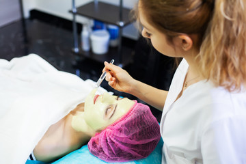 Fototapeta na wymiar Spa therapy for young woman having facial mask at beauty salon.