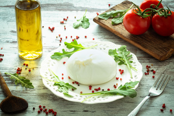 Burrata, Italian cheese with tomatoes, spices, argugula and olive oil and balsamic vinegar