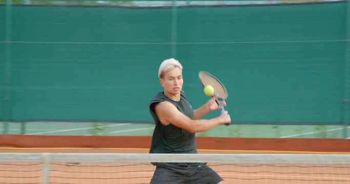 A platinum haired mixed race tennis player volleys a shot over the net and celebrates in slow motion.