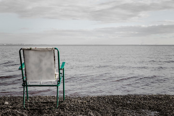  an empty chair stands on the shore of the bay. horizon view