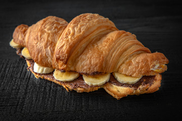 Croissant sandwich with chocolate and banana. Healthy, tasty, nourishing snack. Take away food