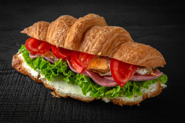 Croissant sandwich with ham, egg, tomatoes, lettuce, sauce. Healthy, tasty, nourishing snack. Take...