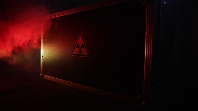Radioactive (atomic ionizing radiation) danger warning symbol in triangular on a black case. Black suitcase with a sign of radiation hazard. Dark background.