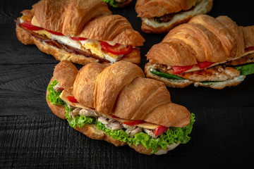 A lot of Croissants sandwich with boiled chicken, mushrooms, cheese, tomatoes, and different toppings. Healthy, tasty, nourishing snack. Take away food