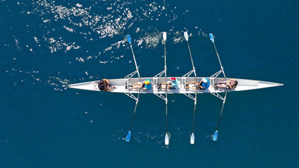 Aerial top down photo of sport canoe operated by team of young men in open ocean deep blue sea