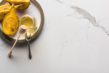 top view of plate with pumpkin and honey and spoon on marble surface