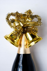 Bottle of champagne decorated with Christmas bells with tinsel o
