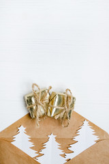 Craft envelope with Christmas trees in it and gift on a white wooden background. Flat lay, Copy space.