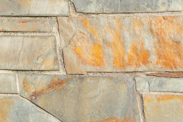 Rugged stone wall with a multi-colored structure with cracks and damage