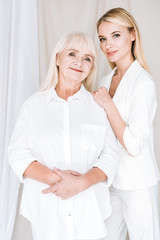 elegant blonde grandmother and granddaughter in total white outfits