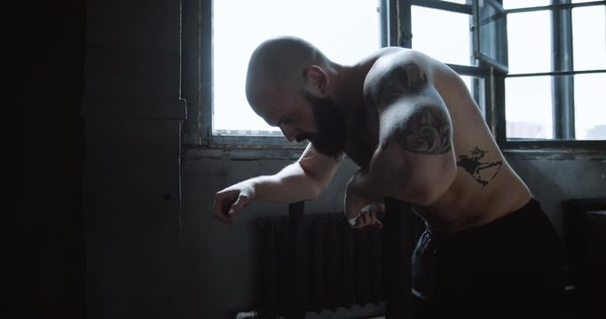 Young muscular Caucasian male athlete is exhausted after extreme power exercising in large gym, sweat drops slow motion.