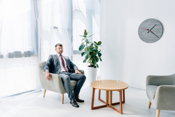 handsome businessman in formal wear and glasses sitting in office