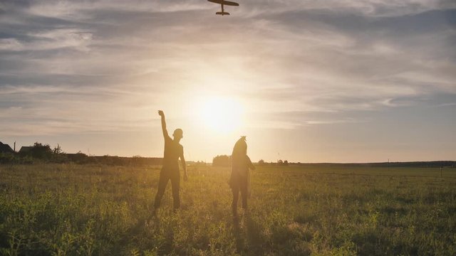 A guy and a girl launch a paralon plane at sunset.