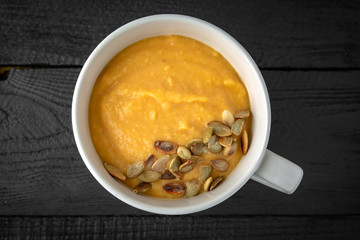 Cream soup made of pumpkin, spinach, broccoli and lentils with parmesan, pumpkin seeds and cream. Tasty, healthy nutritious lunch.