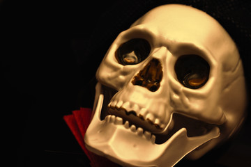 Creepy smiling golden skeleton skull close up on black background with copy space, death and mystery concept, halloween