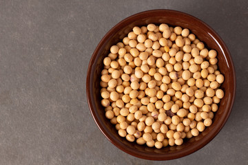 raw and fresh soy beans inside brown ceramic bowl on rustic wooden table..