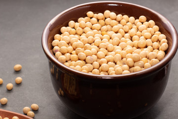 raw and fresh soy beans inside brown ceramic bowl on rustic wooden table..