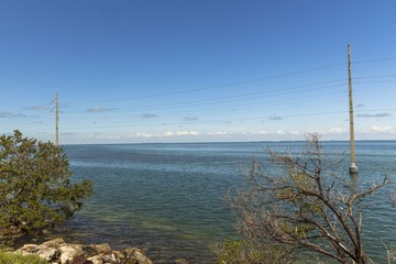 View of Gulf of Mexico coast line. Power line passing through ground water along highway to Key...