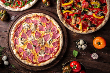 Tasty hot italian pizzas, assorted four cheeses, ham and mushrooms, with salmonon old wooden table. Pizzeria menu. Concept poster for Restaurants or pizzerias