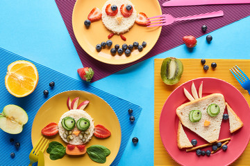 top view of plates with fancy animals made of food on blue and yellow background