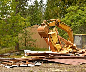 Excavator picking up insulation and boards house demo