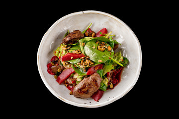 Plate of chicken liver salad with pear isolated at black background.