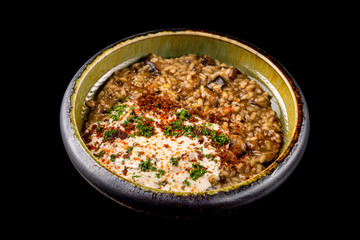 Bowl of risotto with mushrooms and cheese cream isolated at black background.