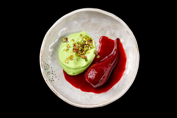 Closeup plate of chocolate mint icecream with syrup and a baked pear isolated at black background.