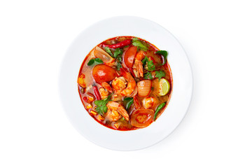 Closeup plate of traditional thai soup - tom yum kung with shrimps and tomatoes isolated at white background.