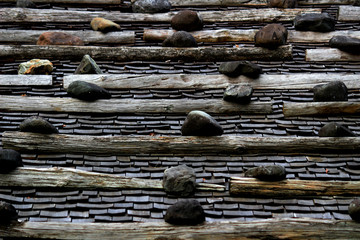 The roof of an old Japanese house made of tile, wood and stone