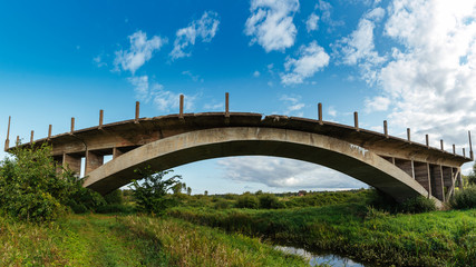 Fototapeta na wymiar Big old abandoned bridge over small river.