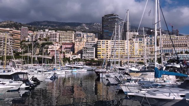 Monaco city harbor with sail boats, downtown buildings and mountain skyline. Royalty free Full HD stock footage related to Mediterranean European life, travel, culture, politics, economics, history. 