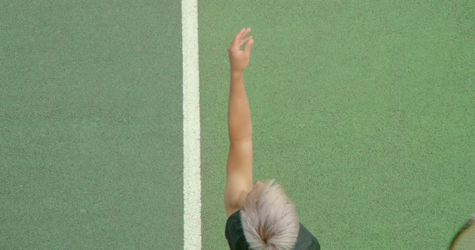 Slow motion close up of a mixed race tennis player serving.