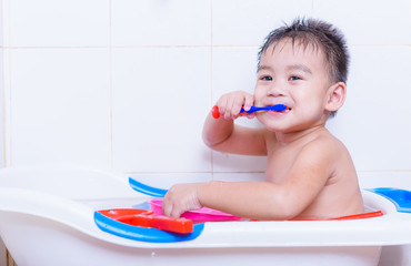 Asian kid brushes teeth with toothpaste on mouth