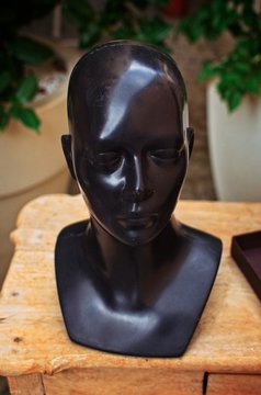 Black head mannequin over a wooden table on a clothing store