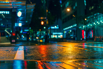 Wet street in downtown Vancouver British Colombia Canada with reflections of orange, red and blue