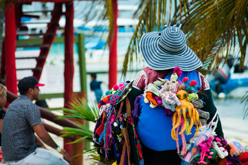 Street vendor woman selling colorful traditional handmade souvenirs near the beach at Puerto Morelos, Mexico