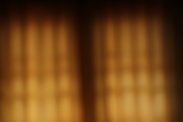 Blured golden brown curtain with glow of light to use as background.