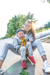 Young happy family smiling having fun, mother little boy 3-5 years old child, have rest on summer autumn day in city park, casual clothes are fun. Joy delight happiness emotions love and care.