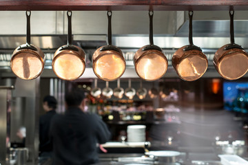 saucepans hanging from a rack in busy kitchen
